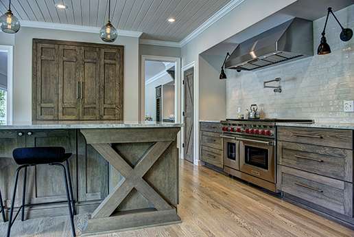 Dark wood cabinetry in country kitchen with shiplap ceiling