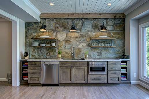 Wood cabinetry and floating shelves with stone backsplash in country kitchen