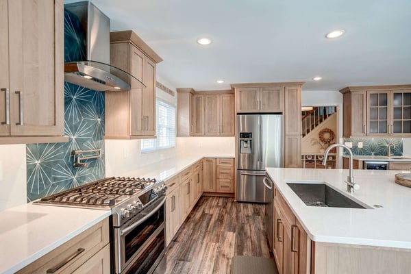 Lightbrown kitchen cabinetry with trendy blue backsplash and white countertops