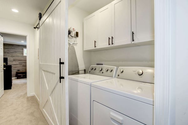 White sliding barn door to hide laundry room machines and cabinets