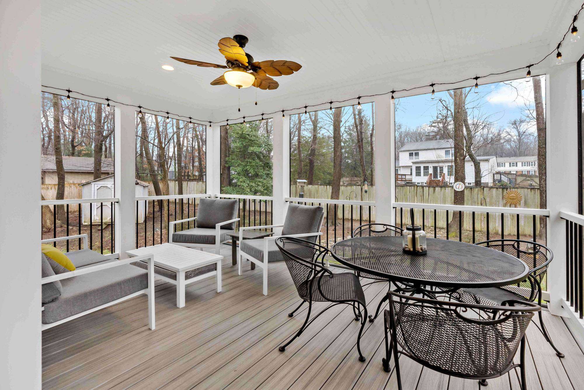 Interior of screened porch with hard wood flooring and ceiling fan