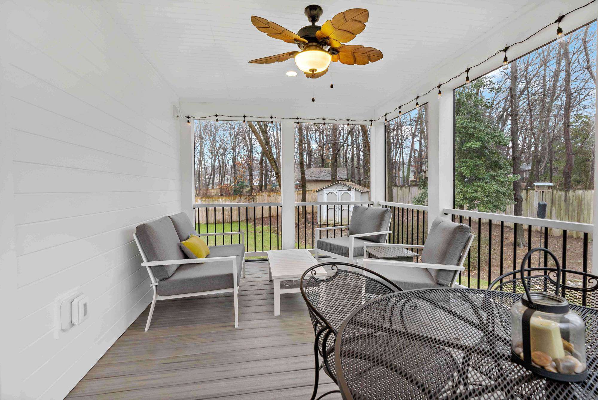 White screened porch with brown ceiling fan and hard wood floors
