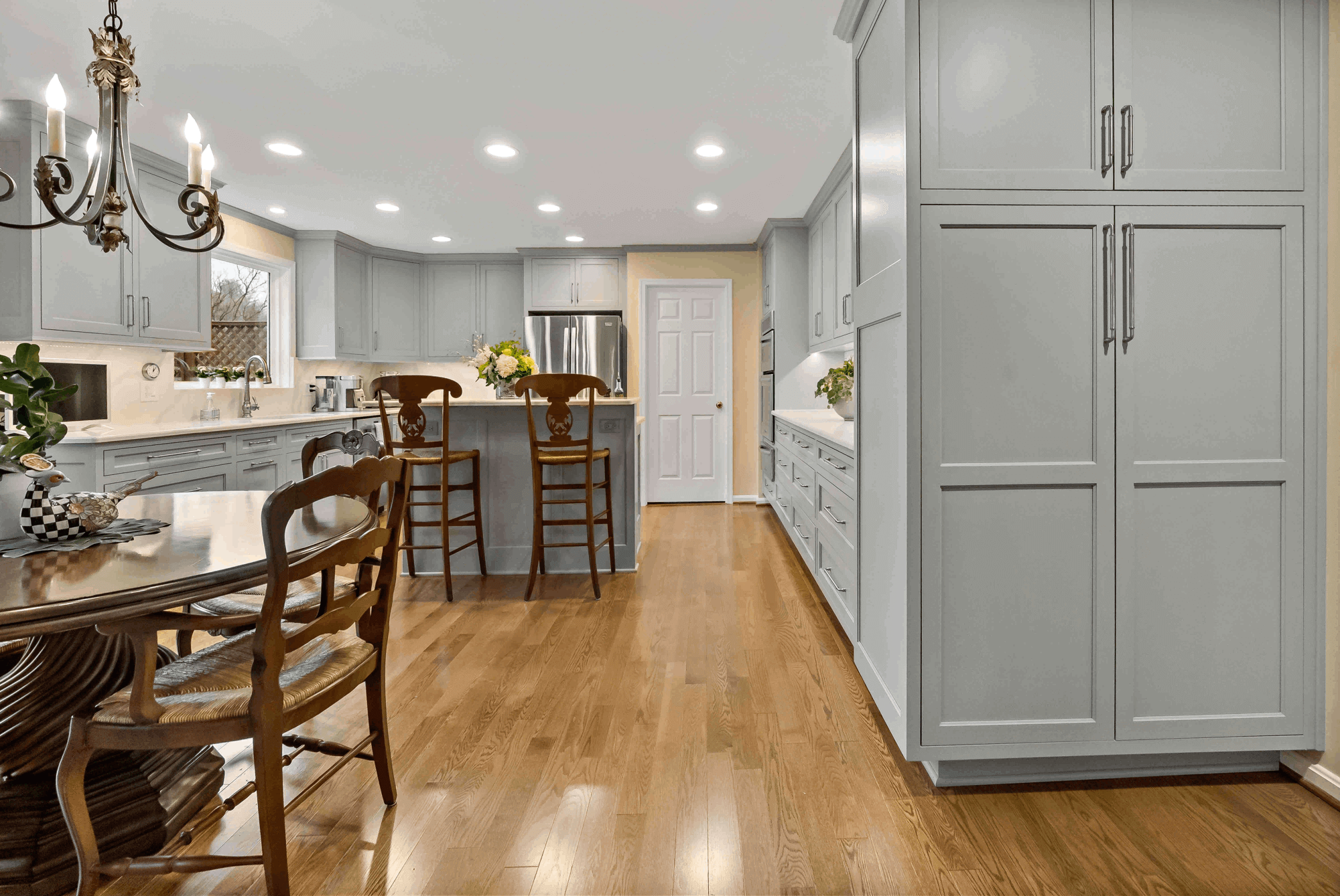 Hard wood floors and wooden chairs in light grey kitchen