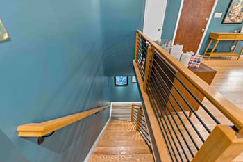 Brown and black railing with blue walls on staircase