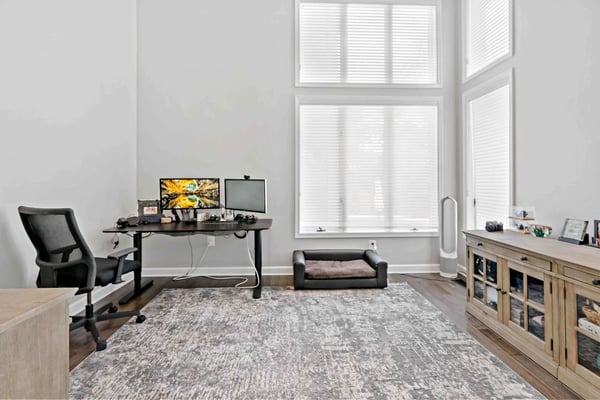 Home office space with high ceilings and white walls and dark hard wood floors