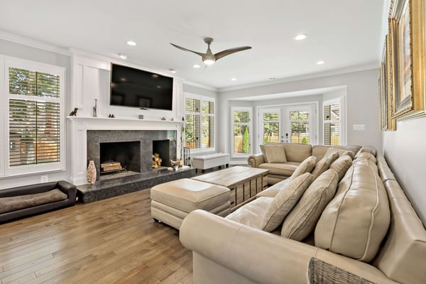 Living room with fireplace, mantle, mounted tv with lots or windows and large couch