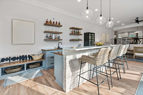 Beverage station bar in home with island seating and floating shelves to display bottles