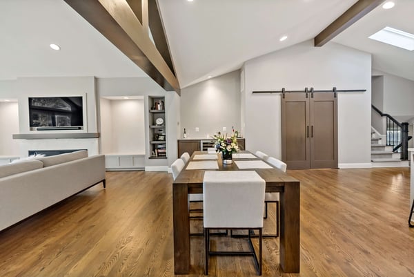 Exposed wood beams in open concept kitchen area with dining table and sliding barn doors