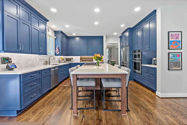 Royal blue kitchen cabinetry with white countertops and large island seating