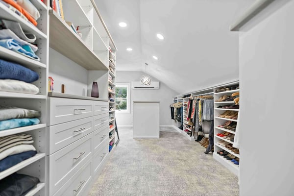 Clean and organized walk-in closet with shelves and cabinets