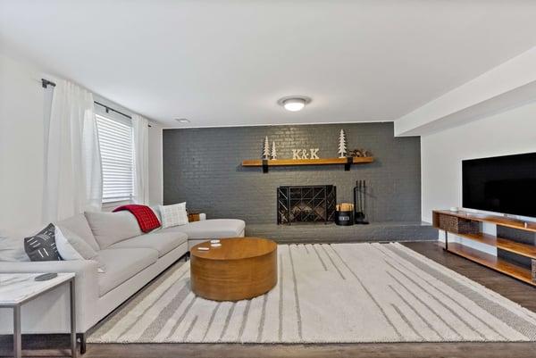 TV room with grey brick accent wall and white curtains