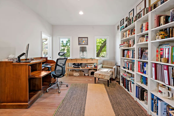 In home office room with large bookshelf and hard wood floors