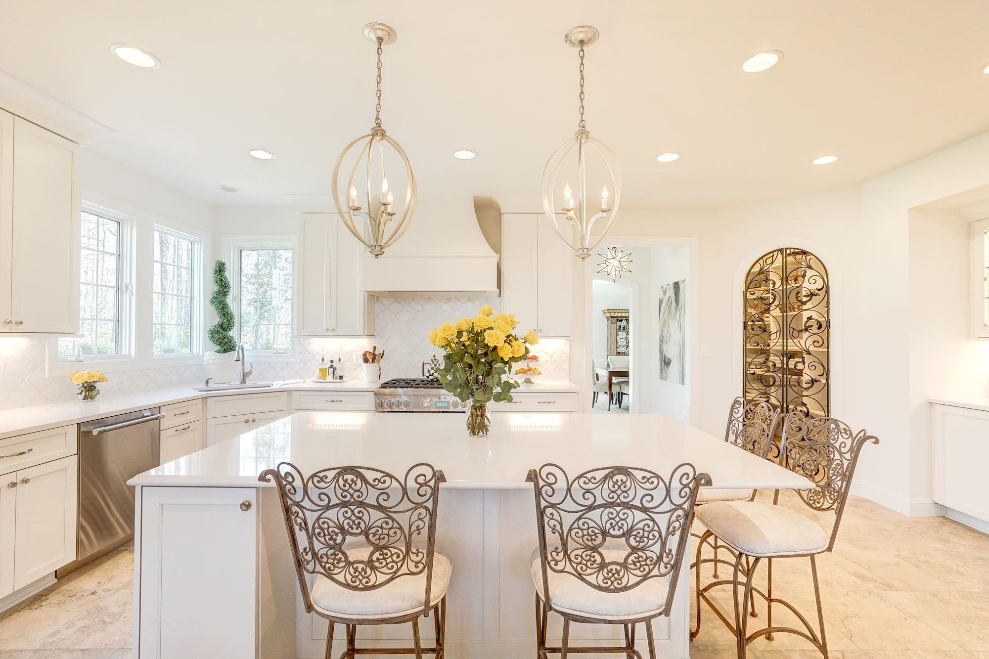 Light-filled kitchen with large kitchen island and unique chair and door details Light-filled kitchen with large kitchen island and unique chair and door details