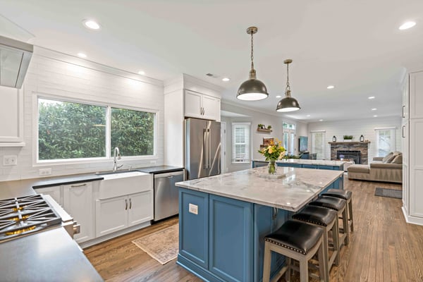 Open concept kitchen with two blue islands and marble countertops