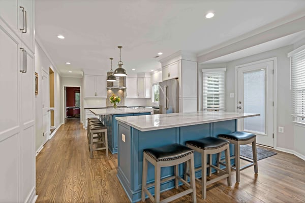 Large kitchen with two blue islands and white cabinets and countertops
