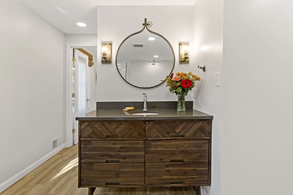 Dark wood cabinetry in bathroom with circle mirror
