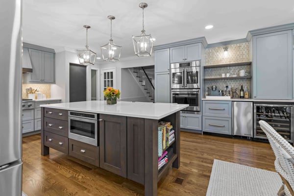 Light blue grey cabinetry in kitchen with dark brown kitchen island and beverage station