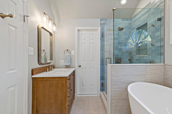 Master bathroom with blue tile walk-in shower and brown gold vanity