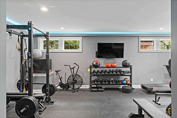 Fully equipped basement gym with blue lights outlining ceiling perimeter