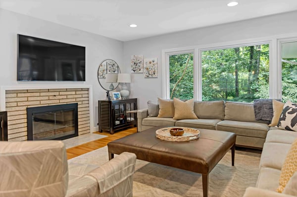 Living room with brown brick fireplace and large windows for backyard views