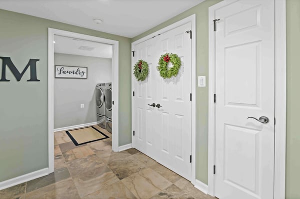 Christmas wreaths hung in hallway by laundry room with green walls in home