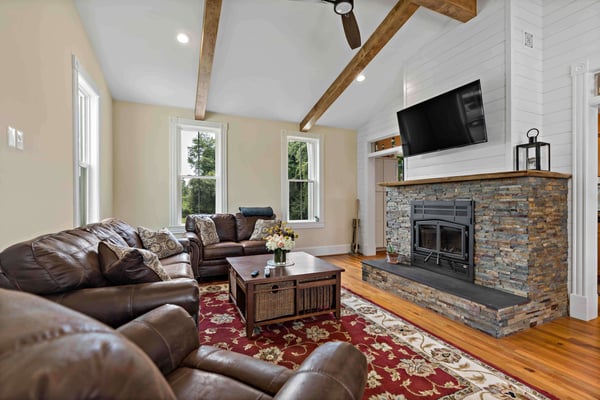 Exposed wood beams and large stone fireplace in living room
