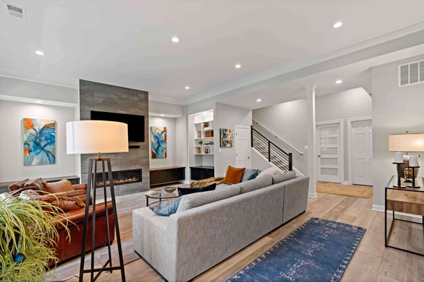 Colorful basement with couches surrounding electric fireplace and mounted tv 