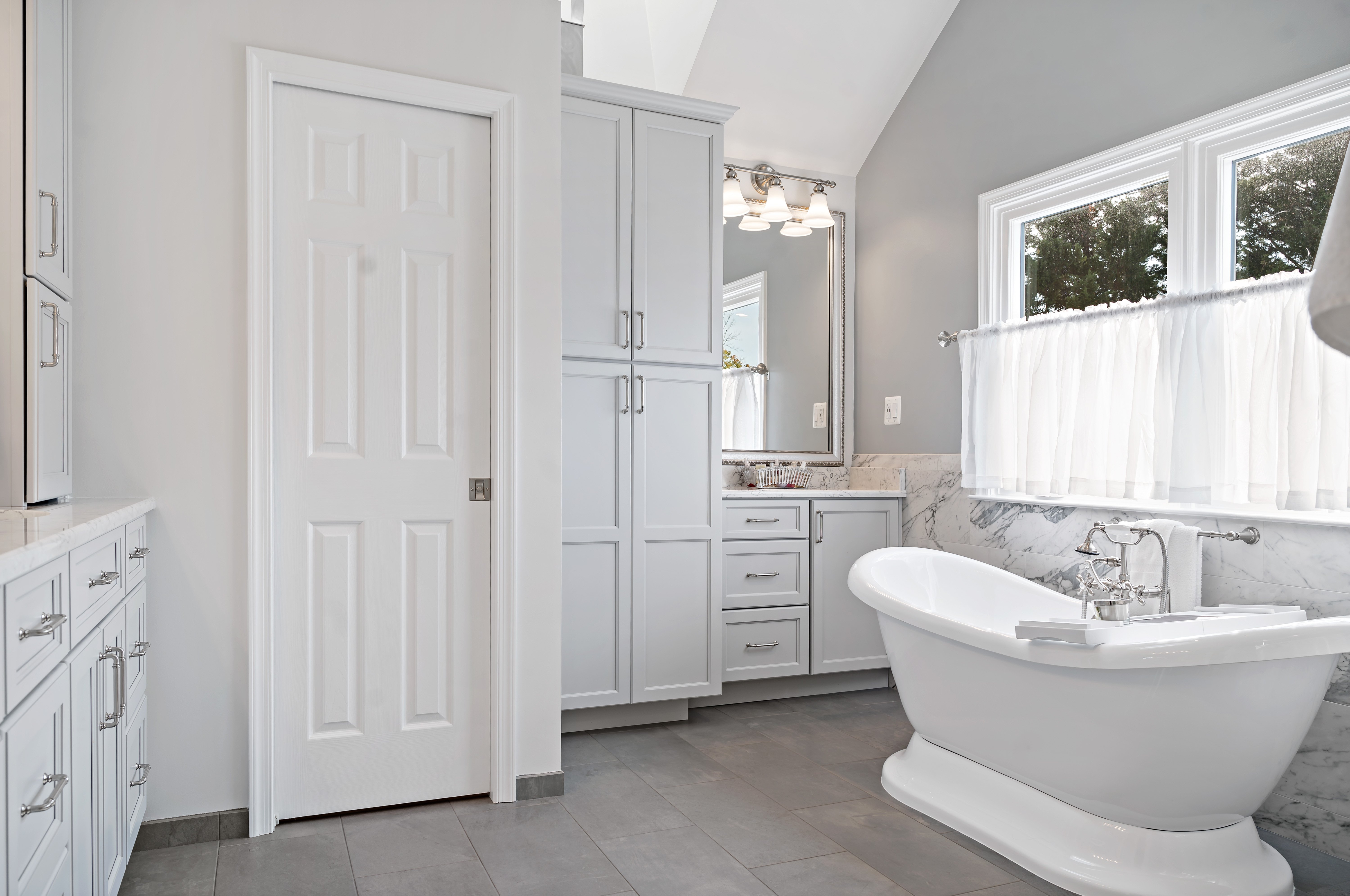 White storage cabinets in full bathroom in Centreville