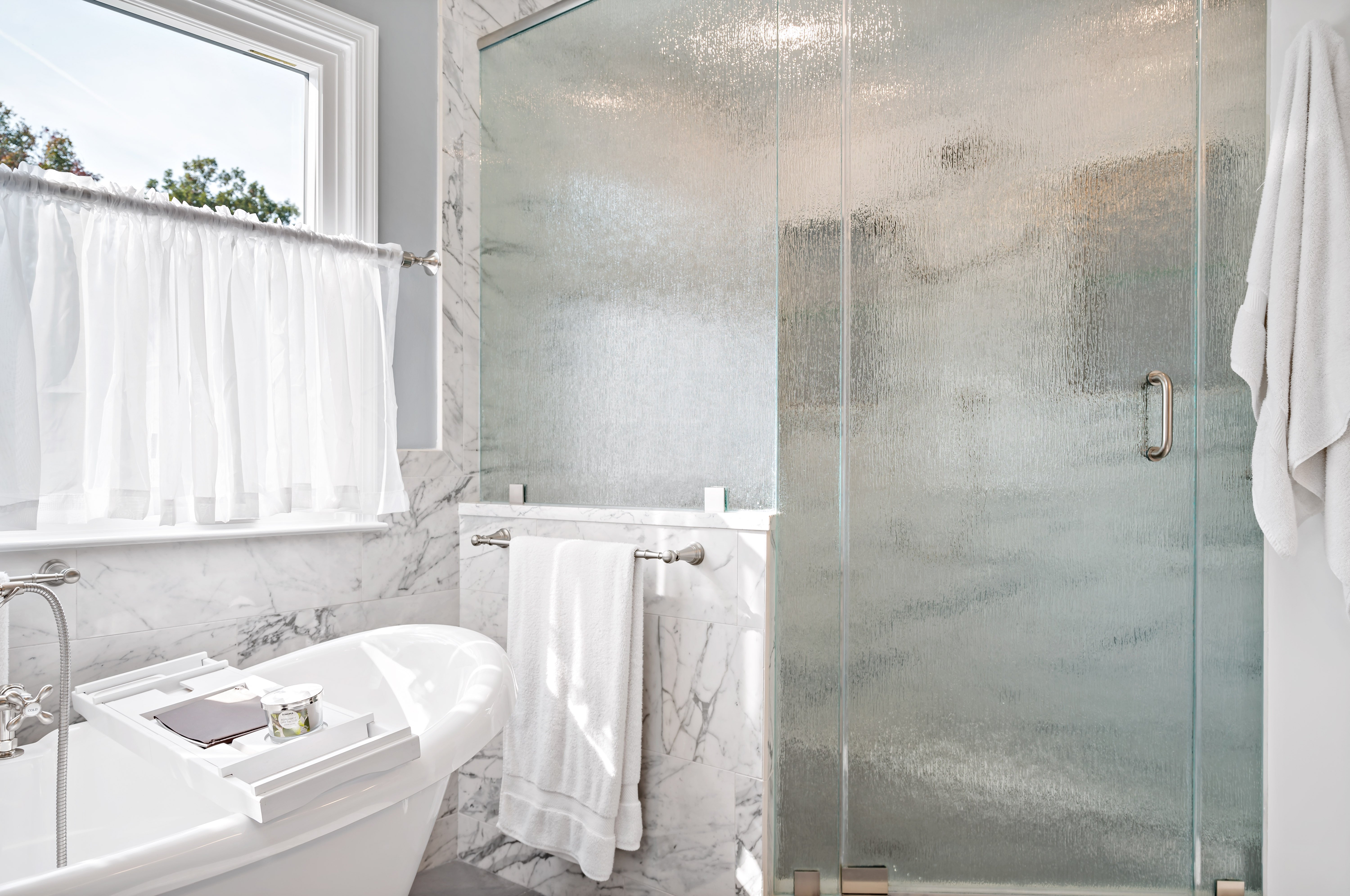 Glass walls and door on stand-up shower in full bathroom with tub