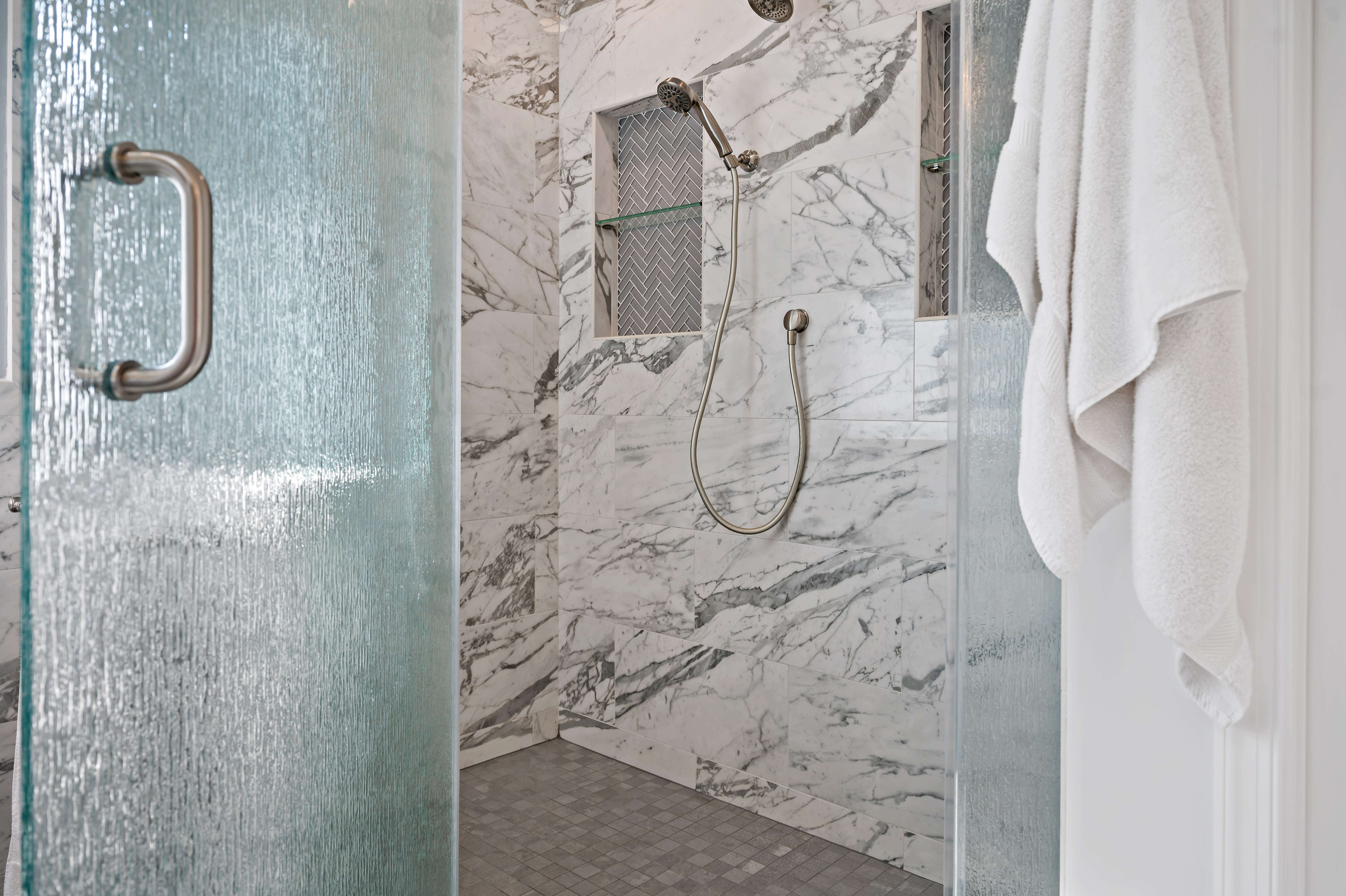 White and black marble walls in stand-up shower with glass door