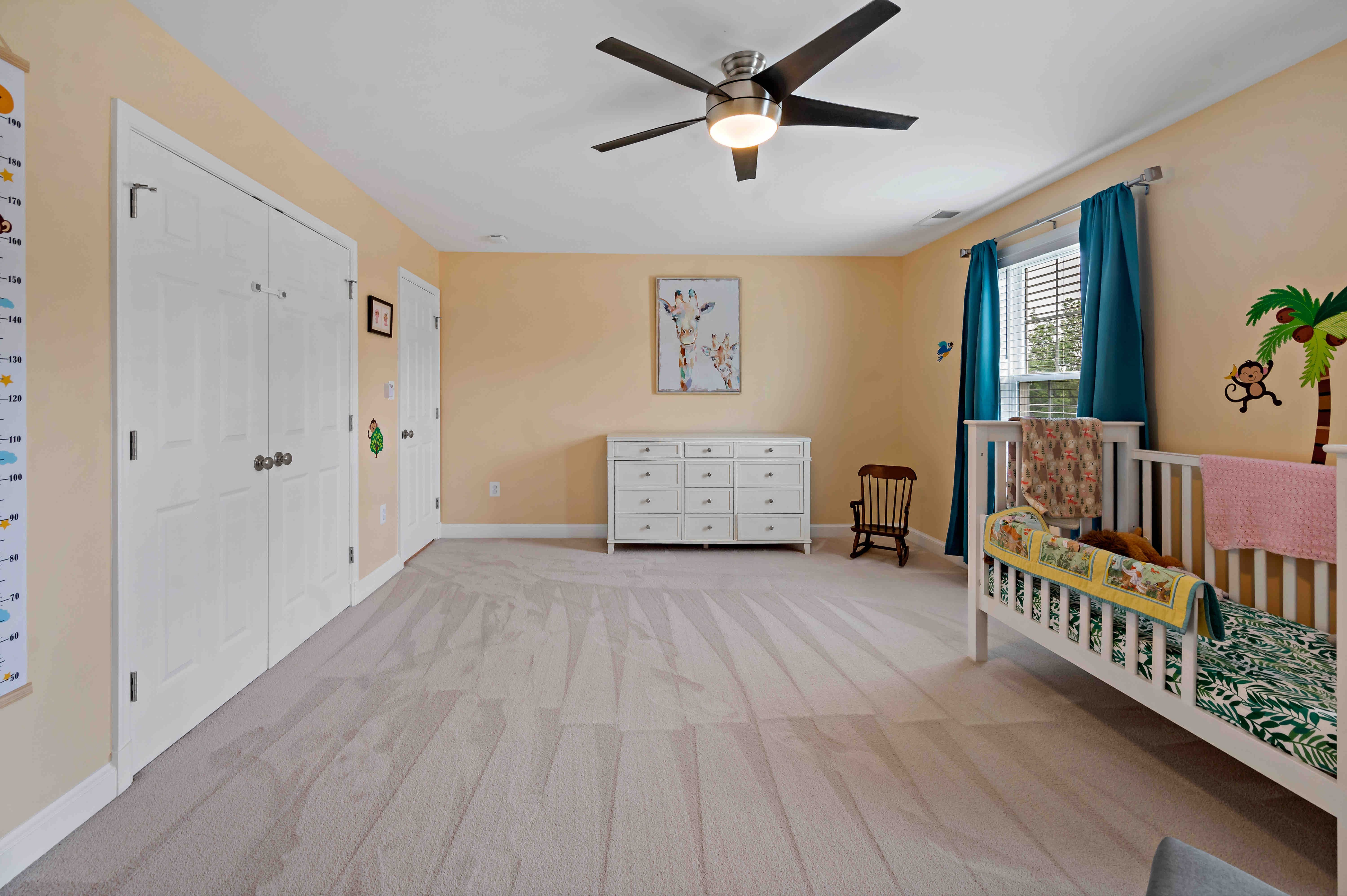Carpeted nursery room with ceiling fan