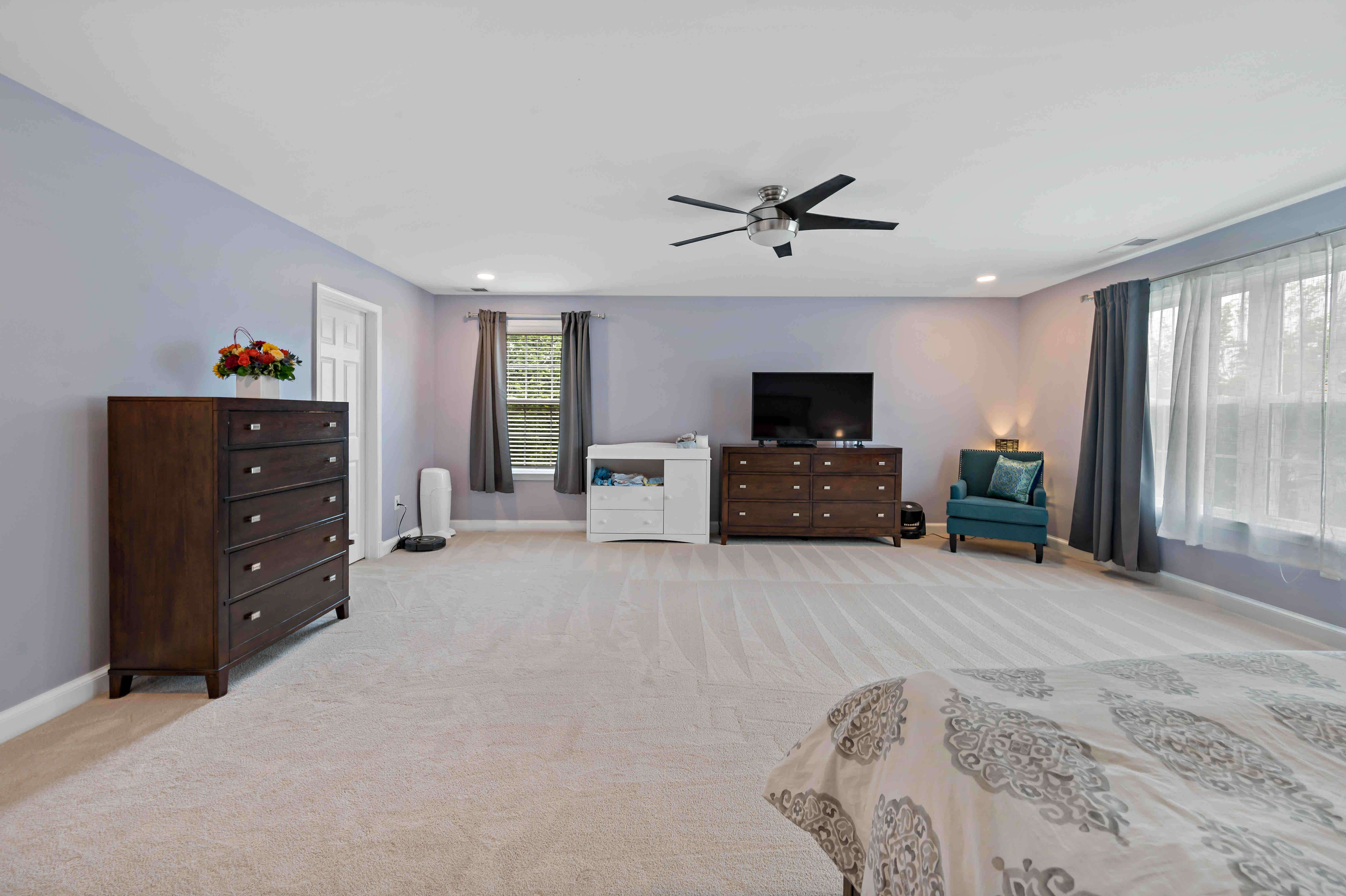 Carpeted master bedroom with window treatment