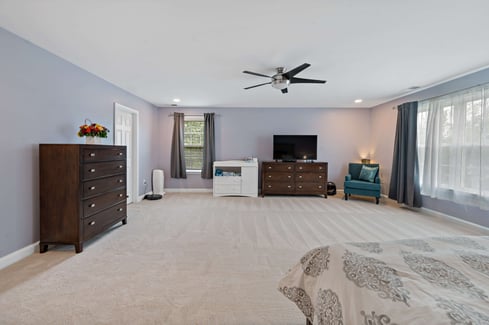 Light colored carpet and light colored purple walls in bedroom