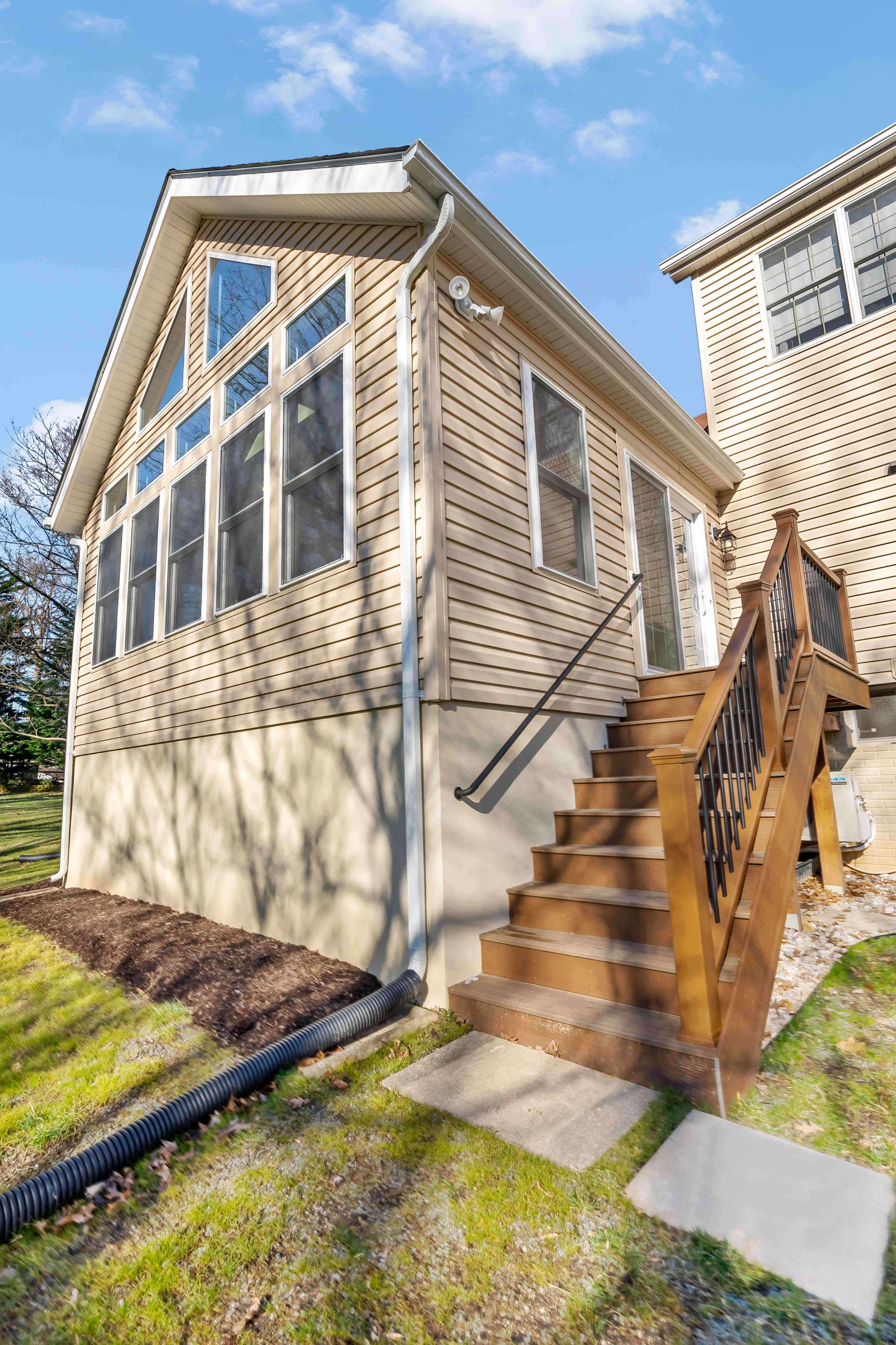 Wooden staircase on side of sunroom leading to backyard
