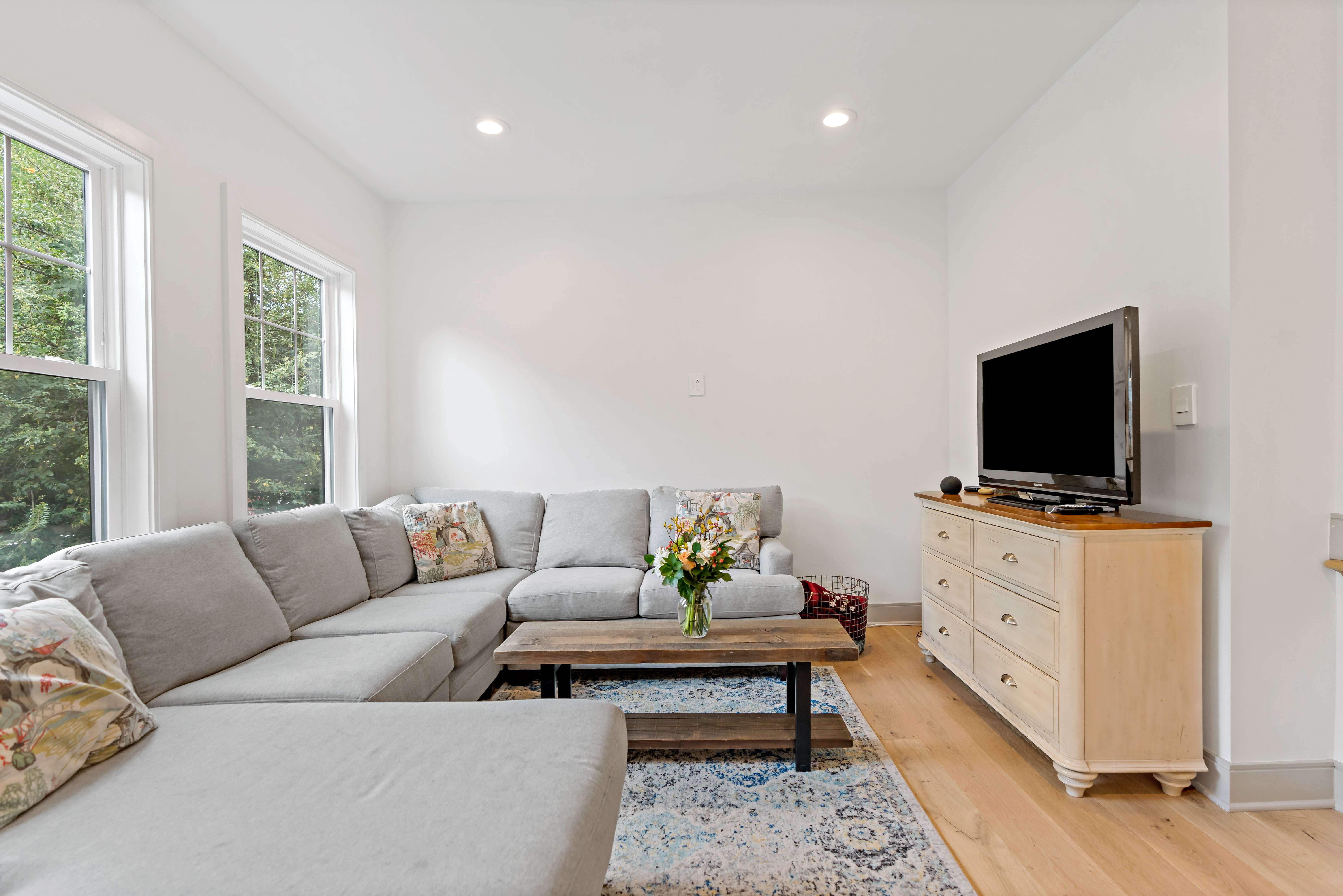 Family room with long grey couch and white walls