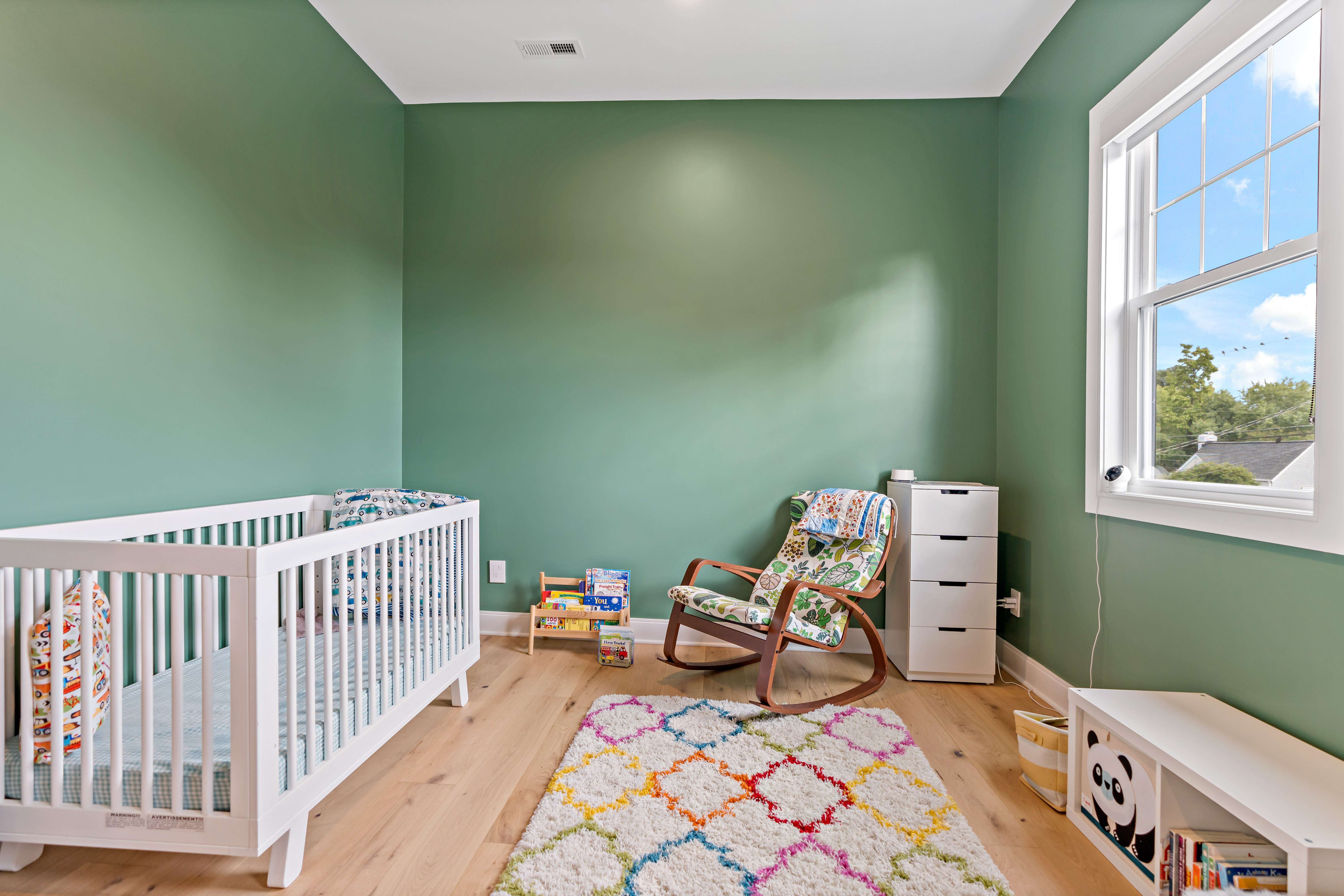Baby nursery room with green walls and hardwood floors