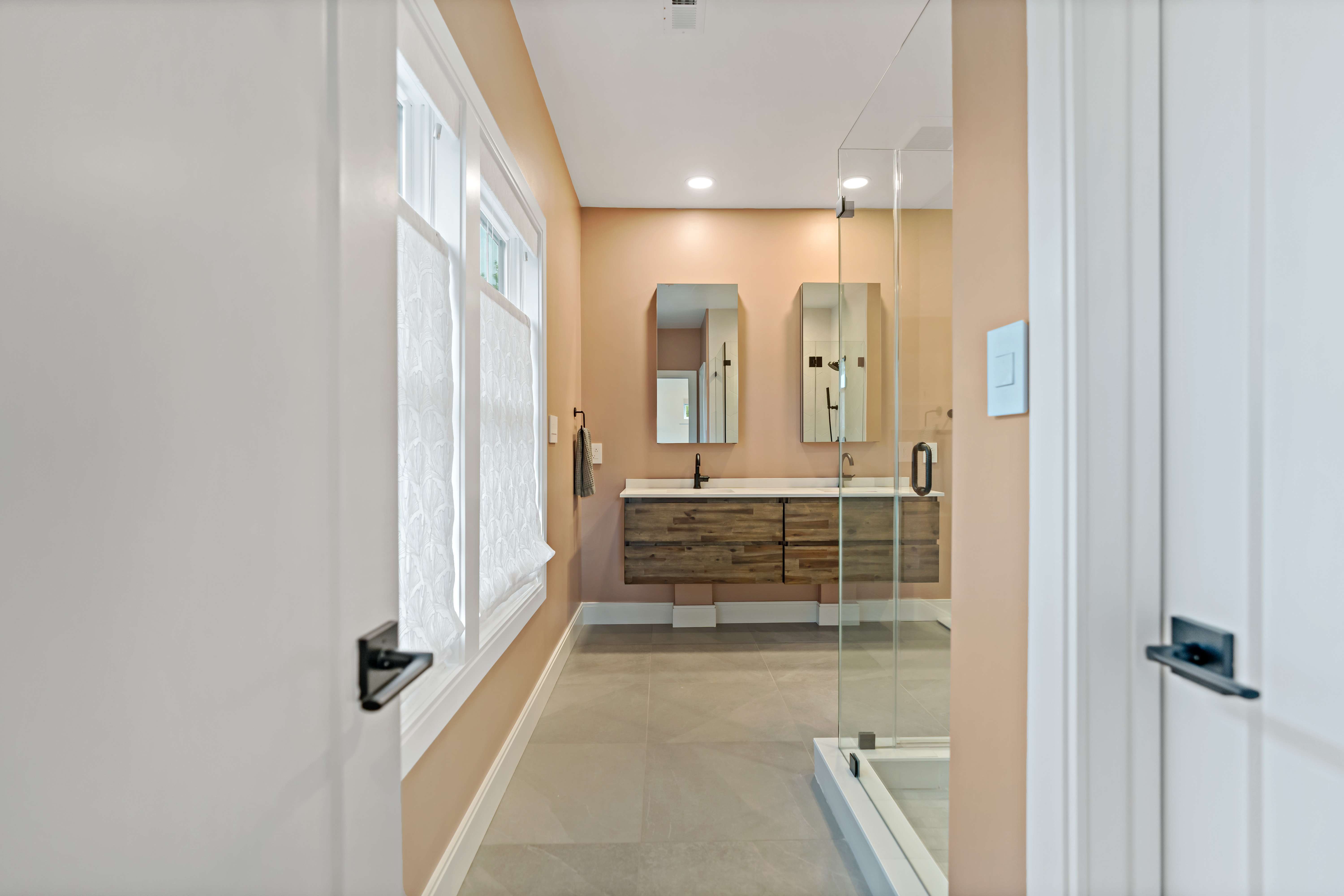 Entryway to bathroom with double sinks and orange walls