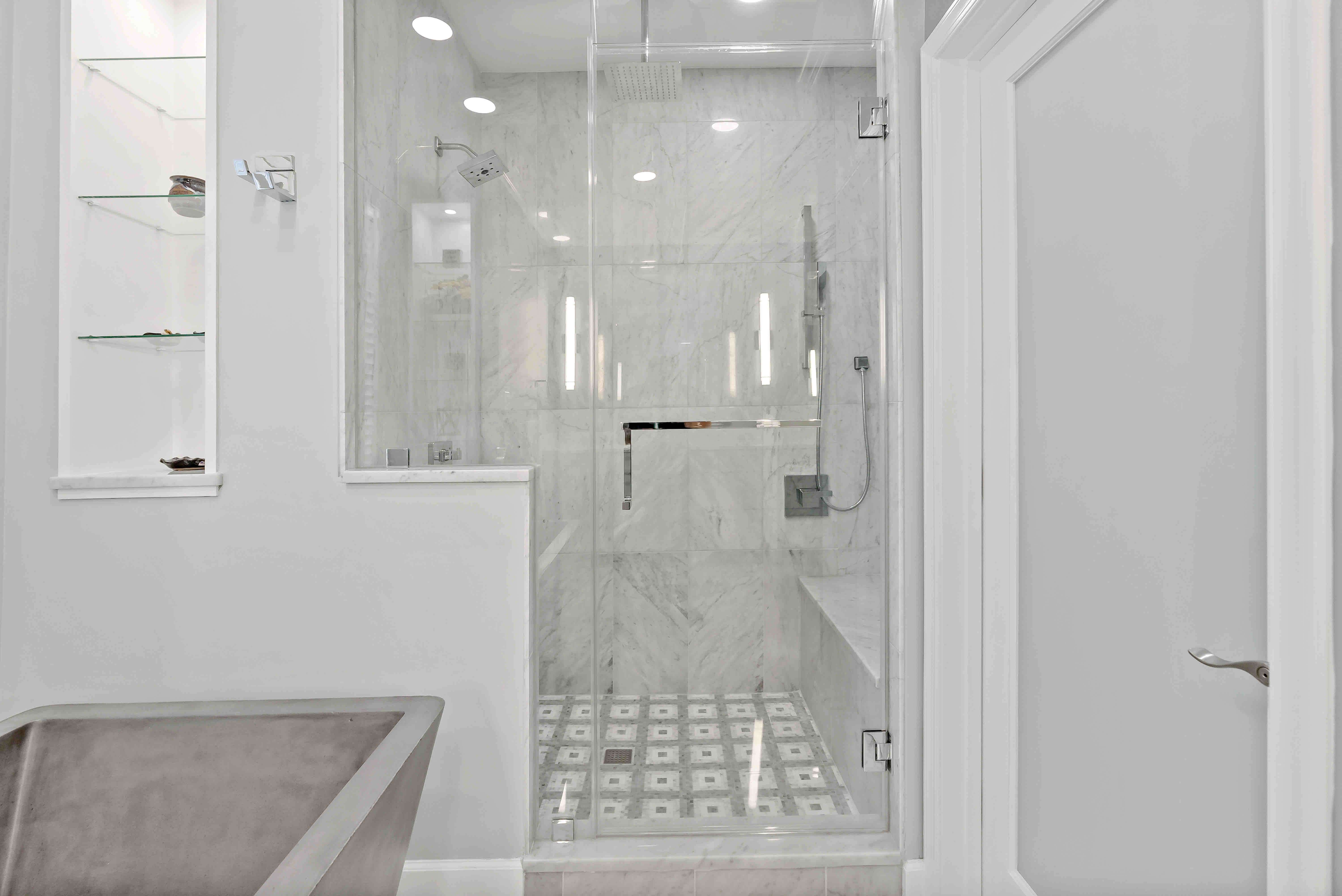 Glass shower door and light grey tiles