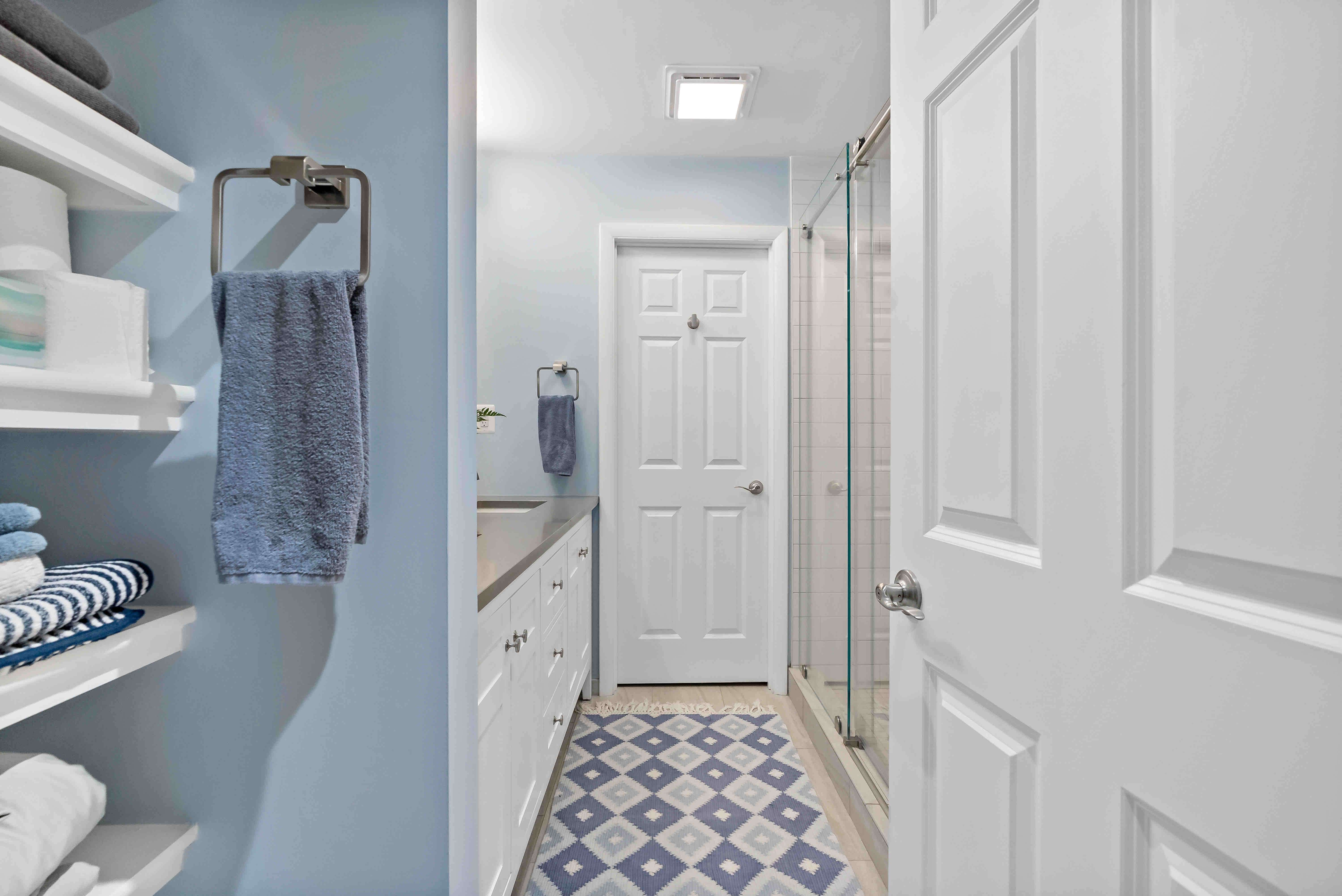 Blue bathroom with stand up shower and white cabinets