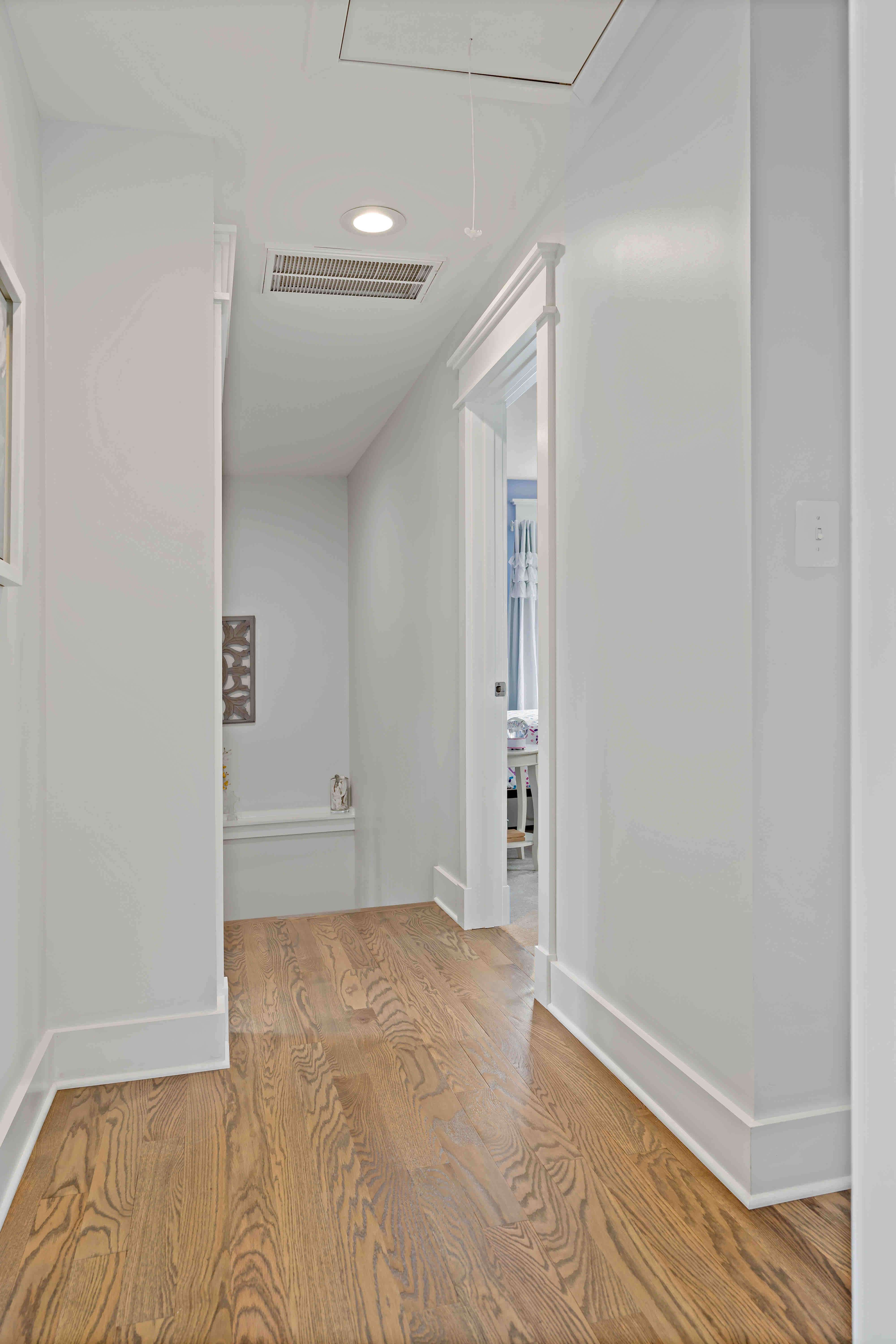 Hallway in house with hardwood floors and white walls