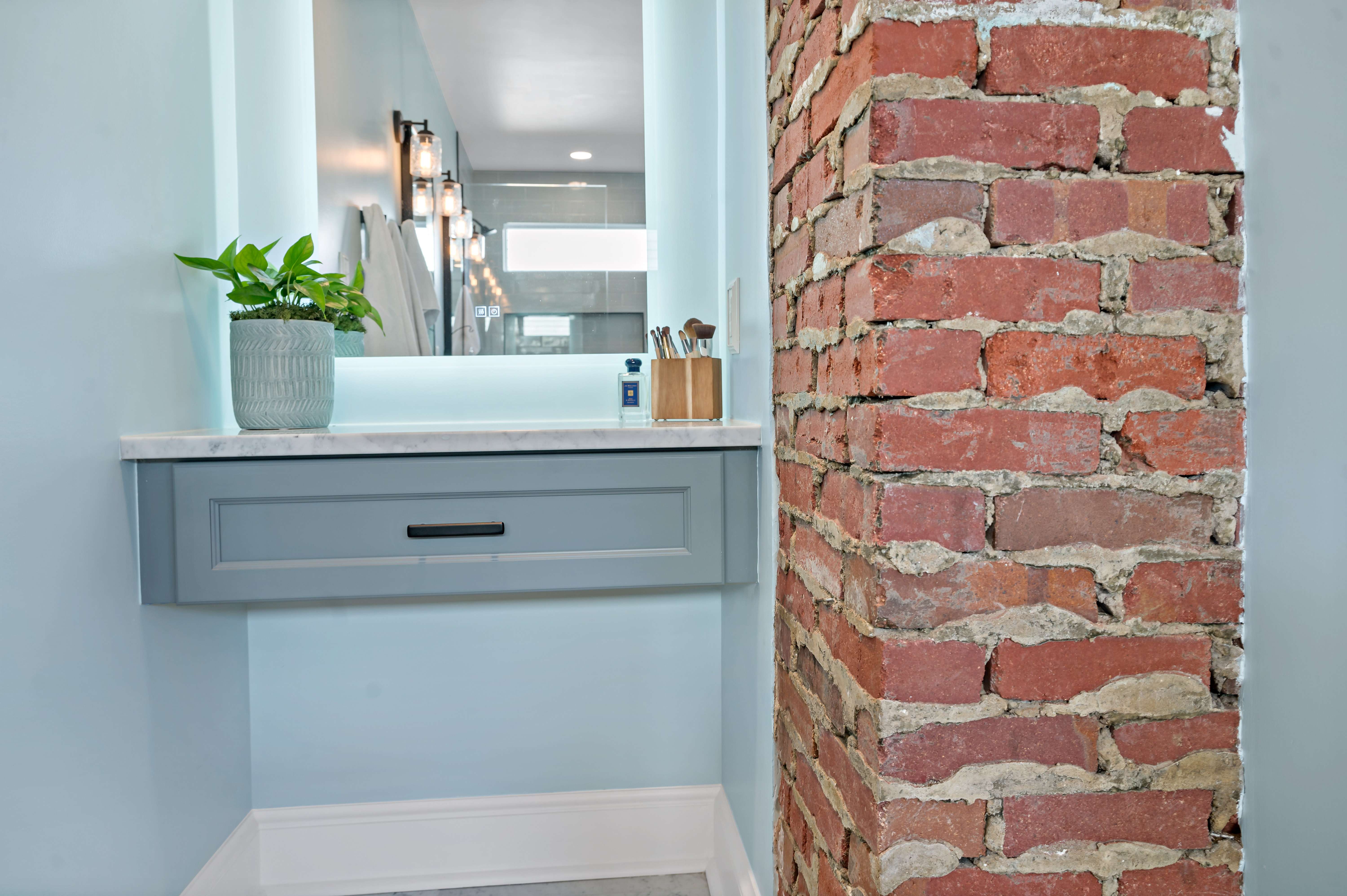 Small vanity area in bathroom with exposed brick