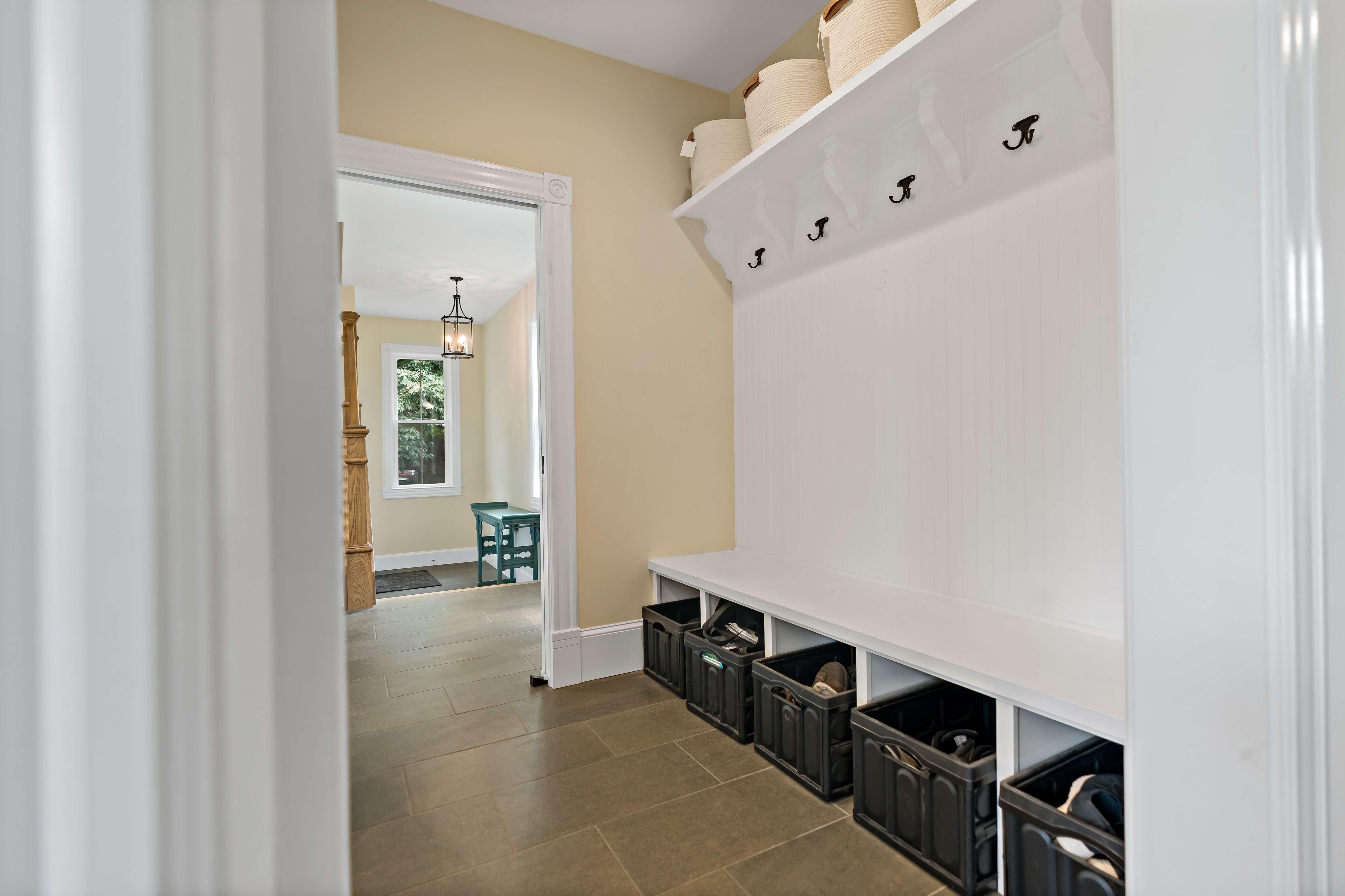 Mudroom with coat hooks next to foyer area and entrance of house