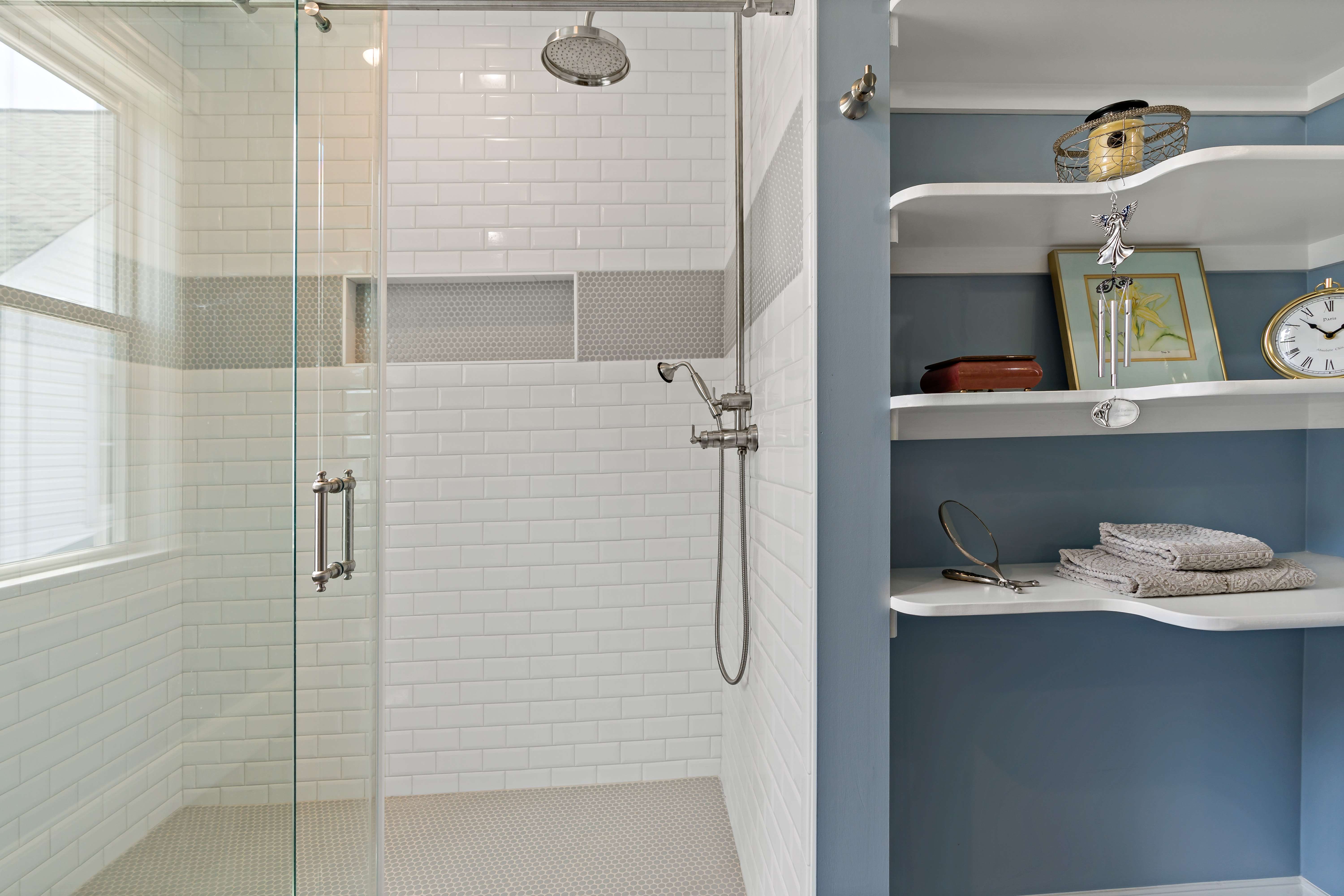 Standup shower with glass walls and built in shelves in bathroom