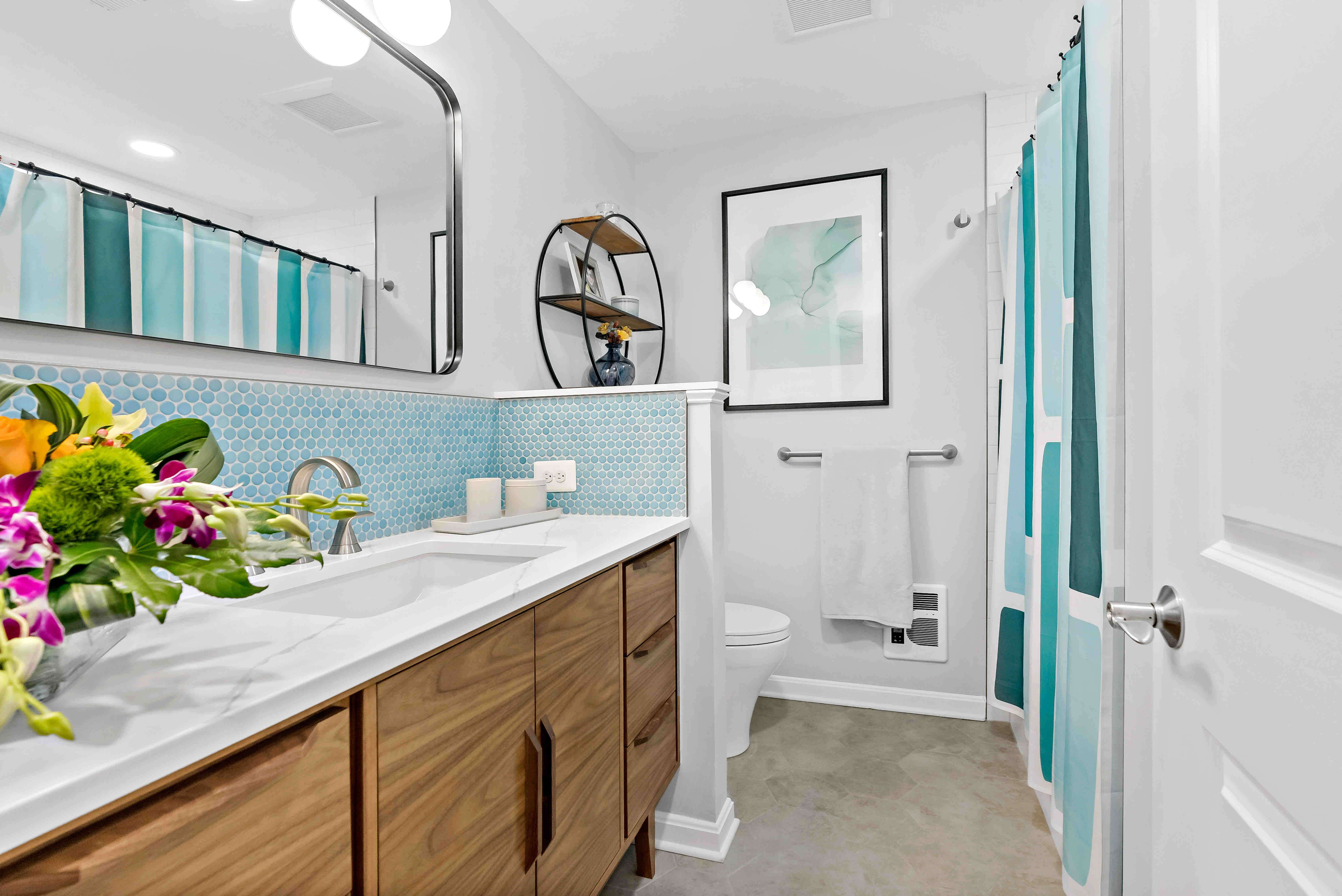 Brown cabinets in bathroom with blue accent backsplash wall behind sink