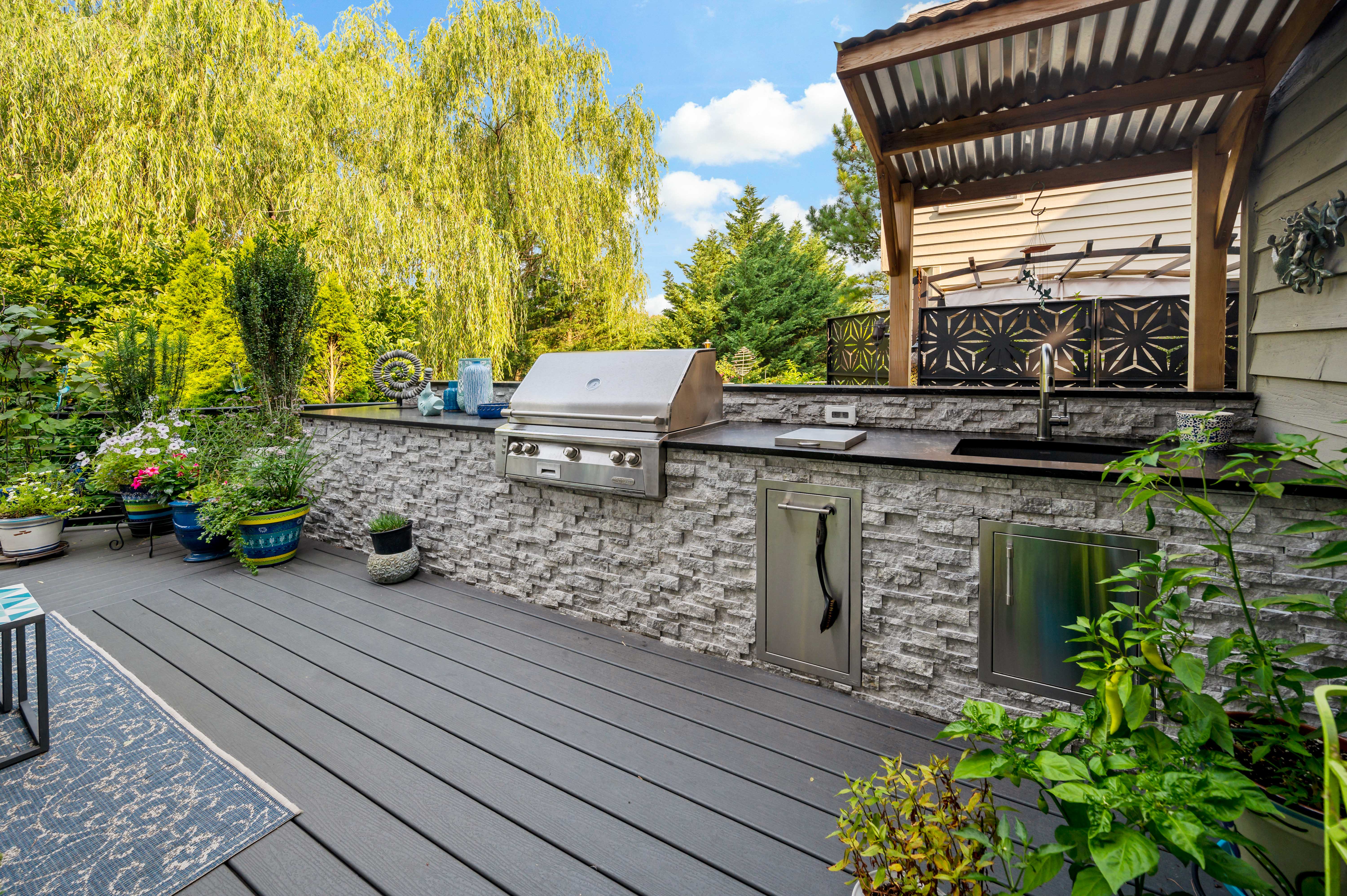 Deck with grey stones surrounding grill and drink fridge