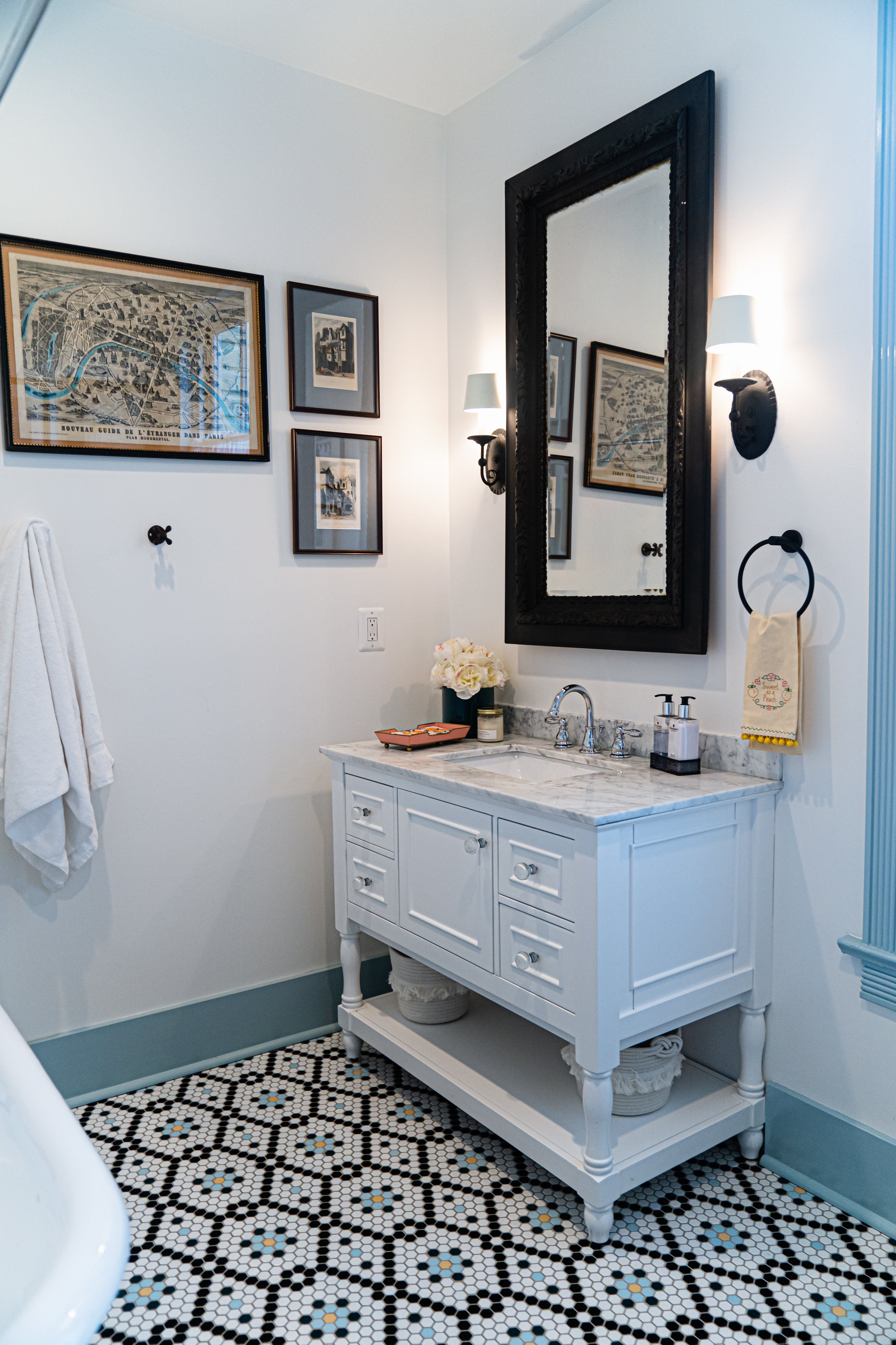 Small bathroom with white cabinets and multiple colored floor tile