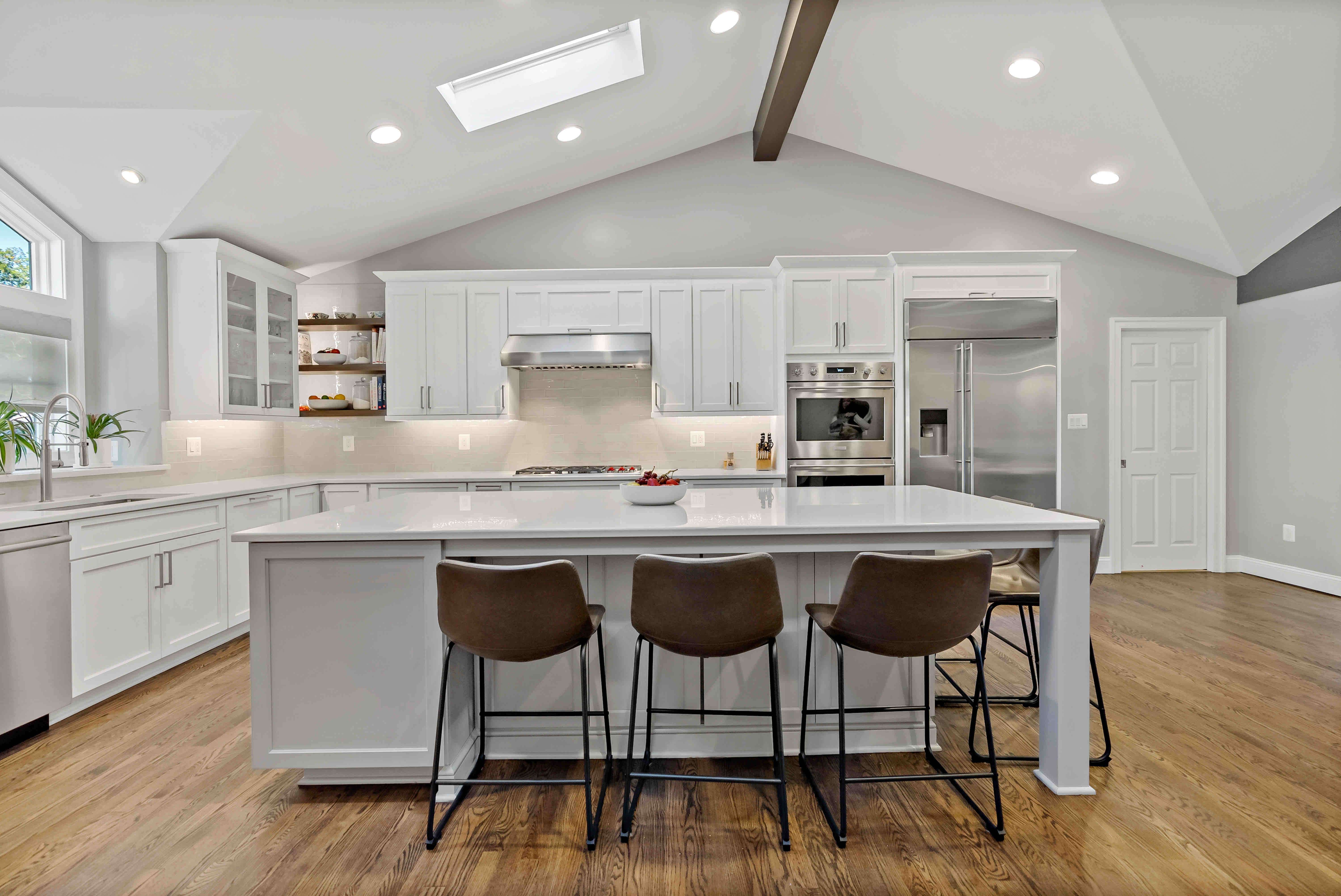 Cathedral ceiling in white kitchen with island seating