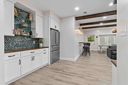 Mini bar on perimeter of basmenet with blue multi-colored backsplash