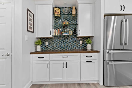 Beverage station and bar with fridge in basmenet with glass shelves and brown countertop