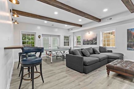 Exposed wood beams and floating bar in remodeled basement